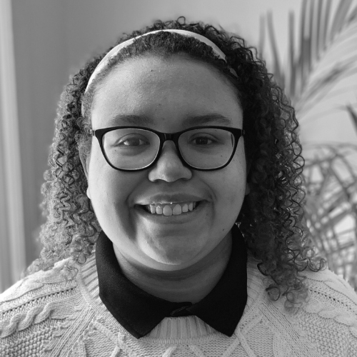 Sinéad is a mixed Black woman with shoulder length curly hair